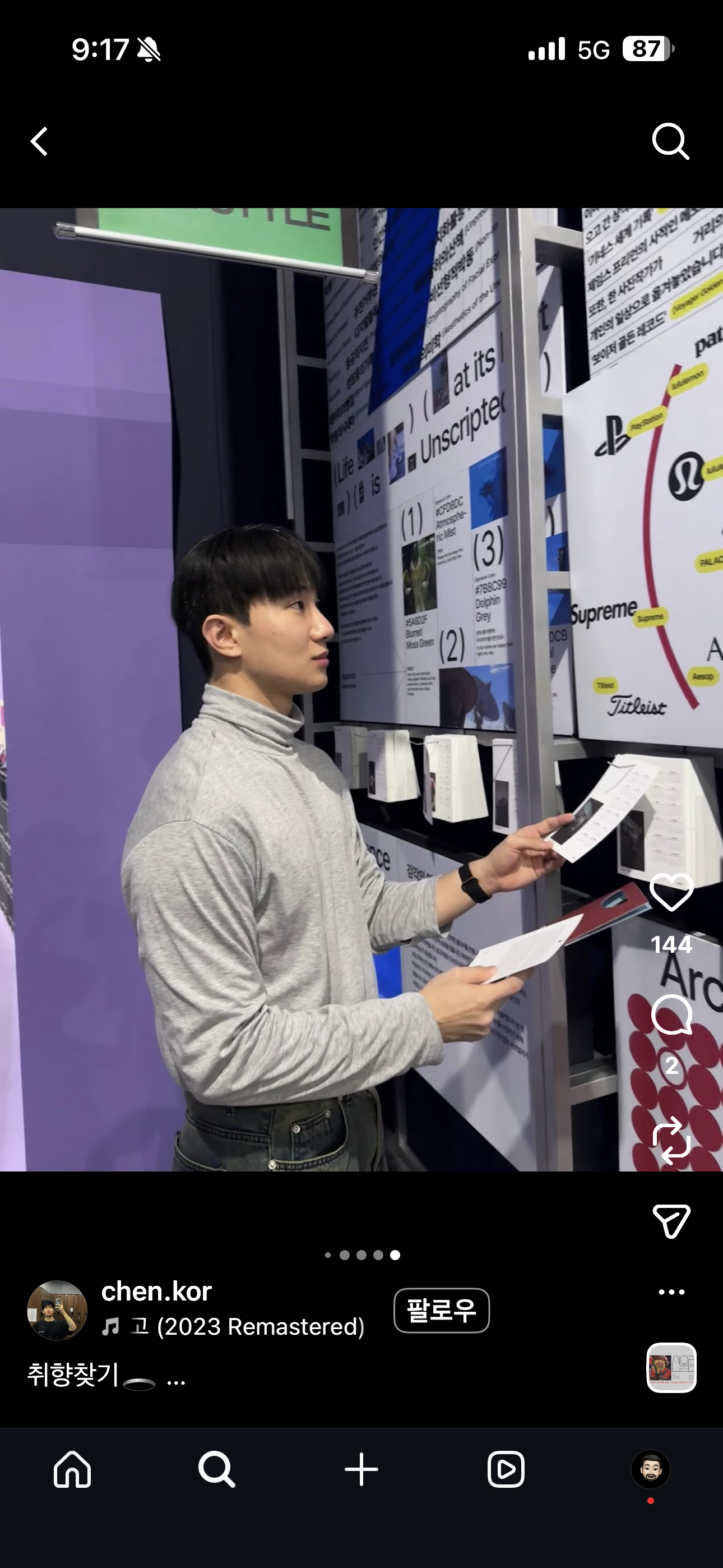 Social screenshot of a visitor holding printed exhibition materials beside the wall display.